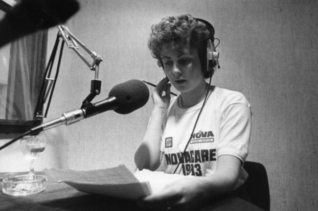 Sybil Fennell reading the news at a Radio Nova microphone